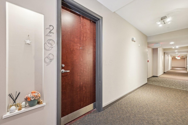 corridor with baseboards and carpet