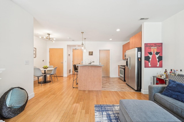 kitchen with a kitchen bar, visible vents, appliances with stainless steel finishes, light countertops, and open floor plan