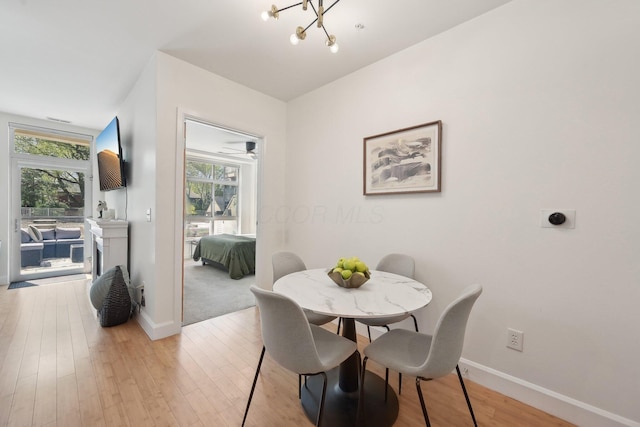 dining area featuring baseboards, plenty of natural light, light wood finished floors, and a notable chandelier