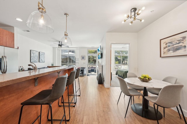 dining room featuring baseboards, visible vents, ceiling fan with notable chandelier, and light wood-style floors