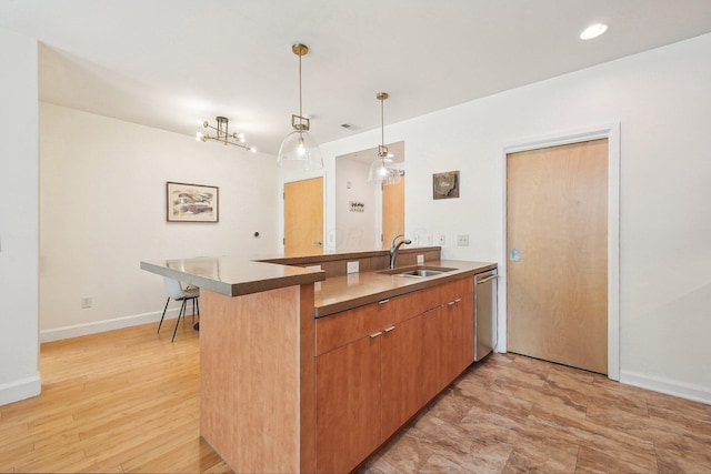 kitchen with hanging light fixtures, a sink, a peninsula, baseboards, and stainless steel dishwasher