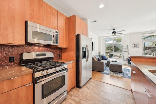 kitchen with open floor plan, decorative backsplash, appliances with stainless steel finishes, and a wealth of natural light