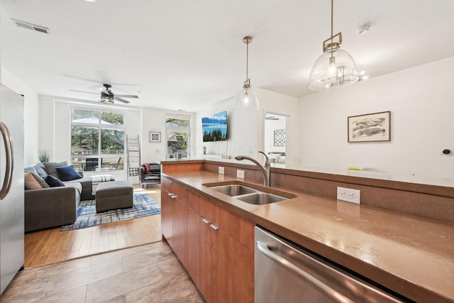 kitchen featuring visible vents, open floor plan, a sink, hanging light fixtures, and stainless steel appliances