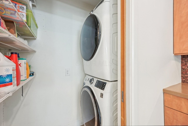 clothes washing area with stacked washer and clothes dryer and laundry area