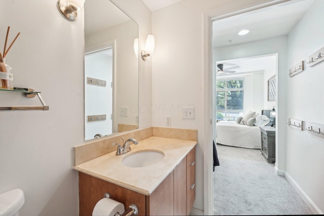 half bathroom with vanity, baseboards, a ceiling fan, and toilet