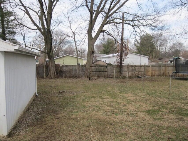 view of yard with a trampoline and fence