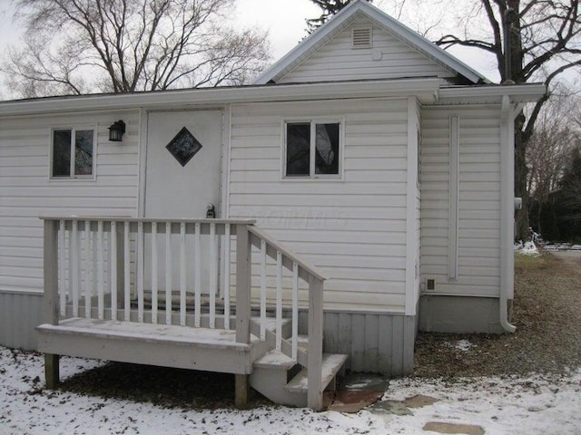 snow covered rear of property with a deck