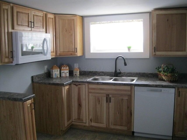 kitchen with a sink, dark countertops, and white appliances