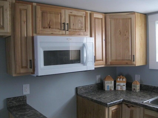 kitchen featuring dark countertops and white microwave