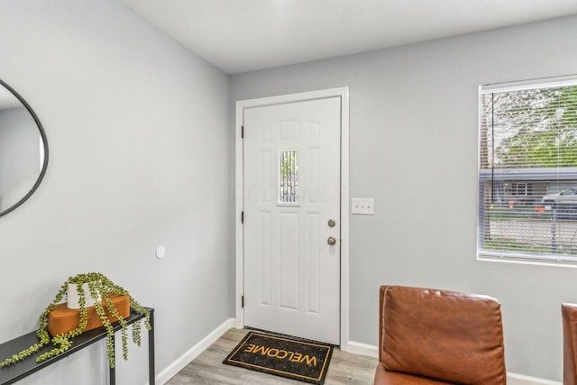 foyer entrance featuring baseboards, light wood-style floors, and plenty of natural light