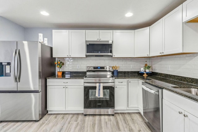 kitchen featuring appliances with stainless steel finishes, dark stone countertops, and white cabinetry