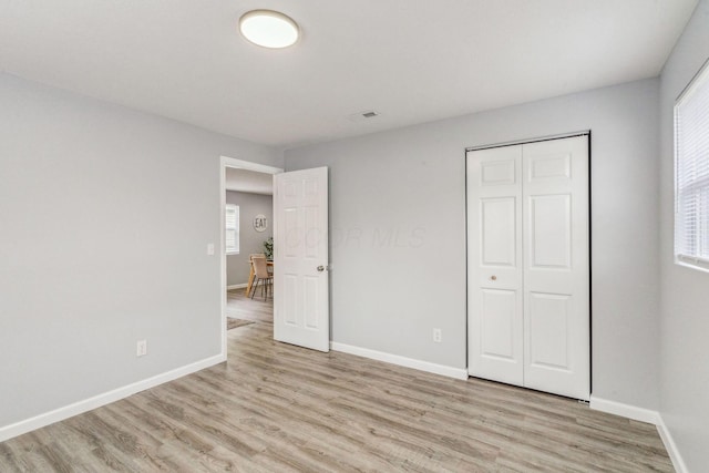 unfurnished bedroom featuring visible vents, multiple windows, and light wood-style floors