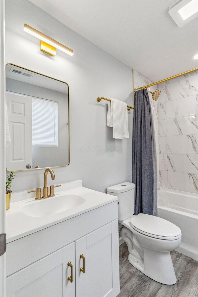 bathroom featuring visible vents, wood finished floors, vanity, toilet, and shower / bath combo with shower curtain