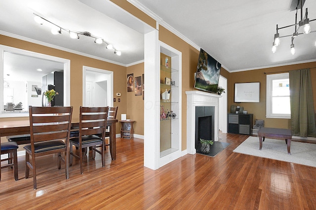 1108 W Church St, Newark, OH 43055 - dining area with rail lighting, wood finished floors, ornamental molding, a fireplace with flush hearth, and baseboards