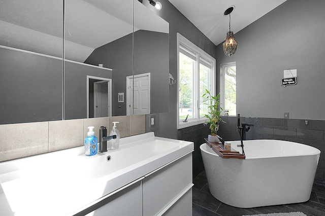 1108 W Church St, Newark, OH 43055 - full bathroom featuring lofted ceiling, a freestanding bath, tile walls, vanity, and tile patterned flooring
