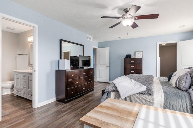 bedroom featuring connected bathroom, dark wood-style flooring, a sink, baseboards, and visible vents