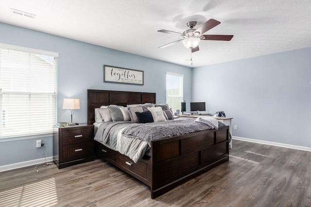 bedroom with baseboards, a ceiling fan, wood finished floors, and visible vents
