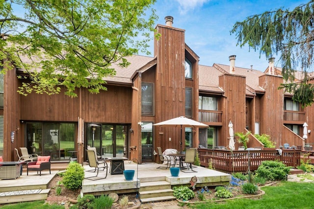 4917 Whistlewood Ln Unit 5, Westerville, OH 43081 - rear view of property featuring a wooden deck, a shingled roof, a chimney, and an outdoor fire pit