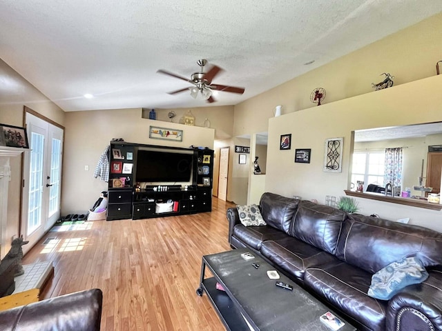 living area with french doors, a ceiling fan, a textured ceiling, wood finished floors, and lofted ceiling