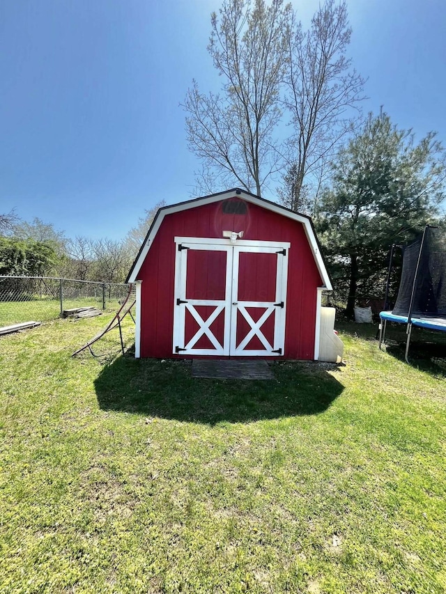 view of shed with fence and a trampoline