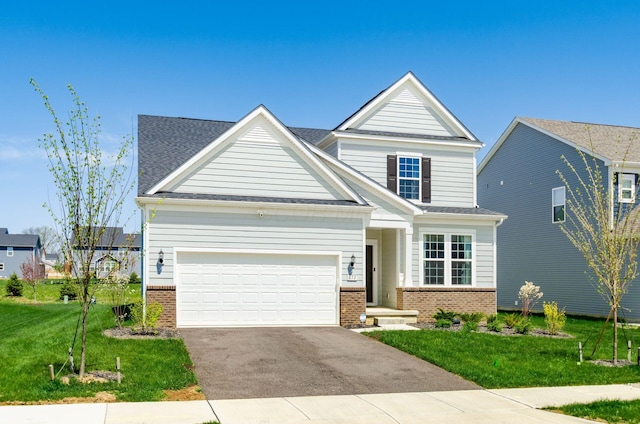 view of front of house featuring brick siding, an attached garage, a front yard, and aphalt driveway