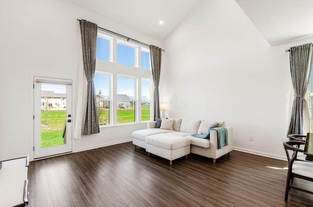 sitting room featuring high vaulted ceiling, dark wood-style floors, and baseboards