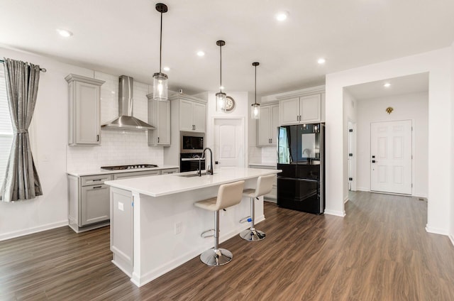 kitchen with decorative backsplash, dark wood-style flooring, wall chimney range hood, appliances with stainless steel finishes, and gray cabinetry