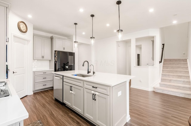 kitchen featuring black fridge, a sink, light countertops, stainless steel dishwasher, and dark wood-style floors