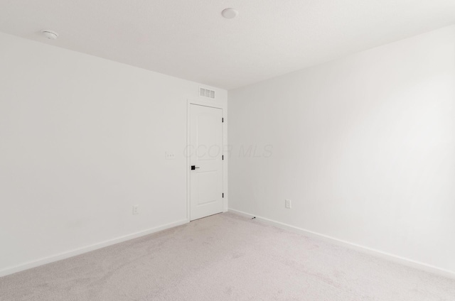 empty room featuring baseboards, visible vents, and light carpet
