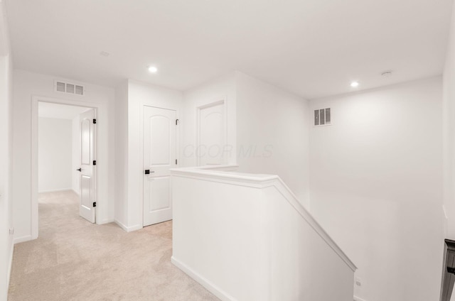 hallway featuring visible vents, baseboards, light carpet, and an upstairs landing