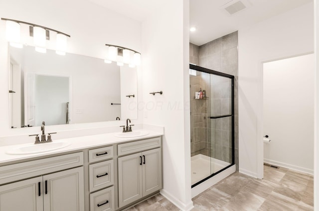 full bathroom featuring double vanity, baseboards, a shower stall, and a sink