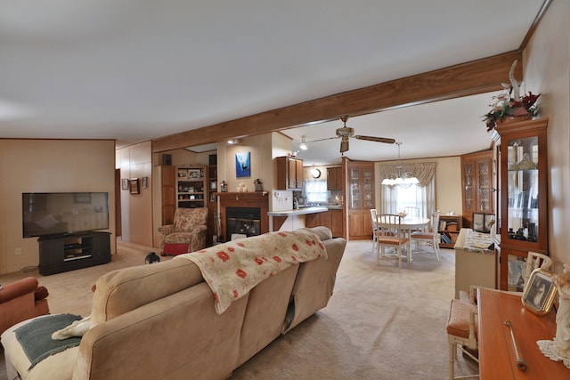 living area featuring beamed ceiling, light carpet, and ceiling fan