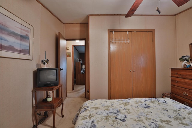 carpeted bedroom featuring ornamental molding, a ceiling fan, and a closet