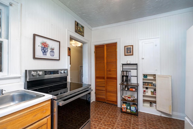 kitchen featuring crown molding, stainless steel electric range, a sink, light countertops, and a textured ceiling