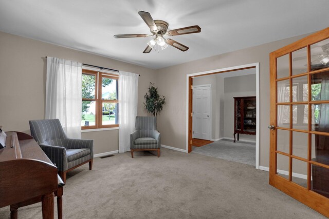 living area featuring carpet flooring, a ceiling fan, baseboards, and visible vents