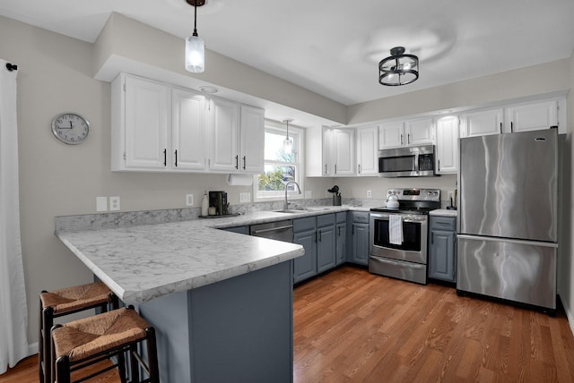 kitchen featuring a sink, stainless steel appliances, white cabinetry, a peninsula, and gray cabinetry