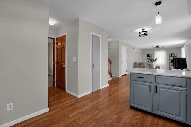 kitchen featuring ceiling fan, wood finished floors, gray cabinetry, baseboards, and open floor plan
