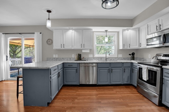 kitchen featuring a sink, a peninsula, gray cabinetry, and stainless steel appliances