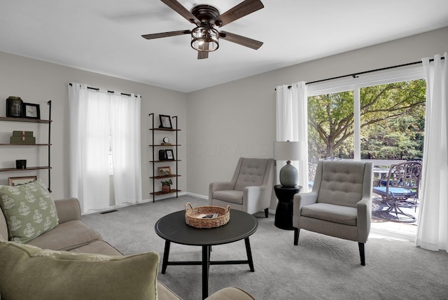 carpeted living area featuring a healthy amount of sunlight, baseboards, ceiling fan, and visible vents