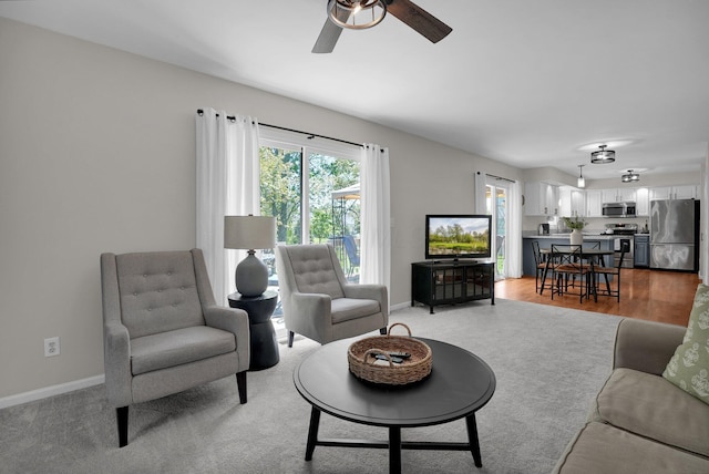 living area with baseboards and a ceiling fan