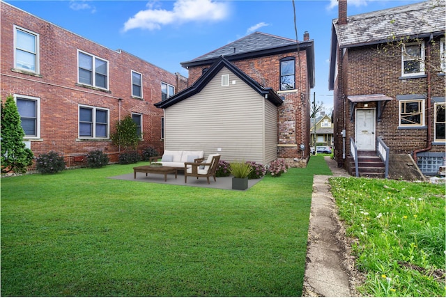 back of house featuring a yard, brick siding, a patio, and an outdoor hangout area