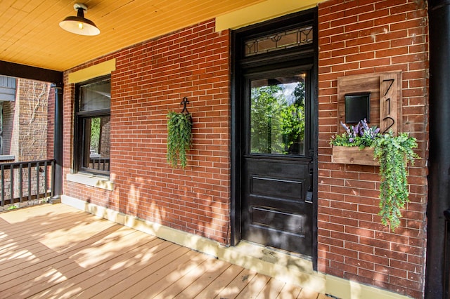property entrance with a porch and brick siding