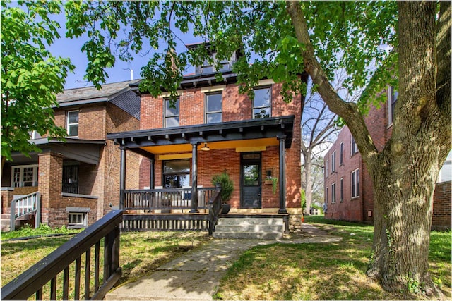 view of front of home with a porch, a front lawn, and brick siding