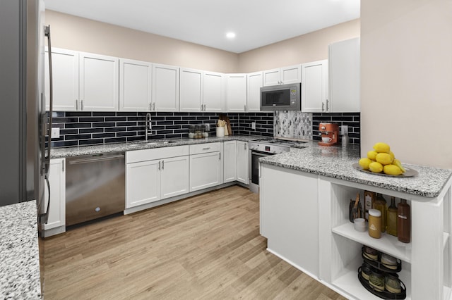 kitchen featuring a sink, decorative backsplash, stainless steel appliances, and light wood-type flooring