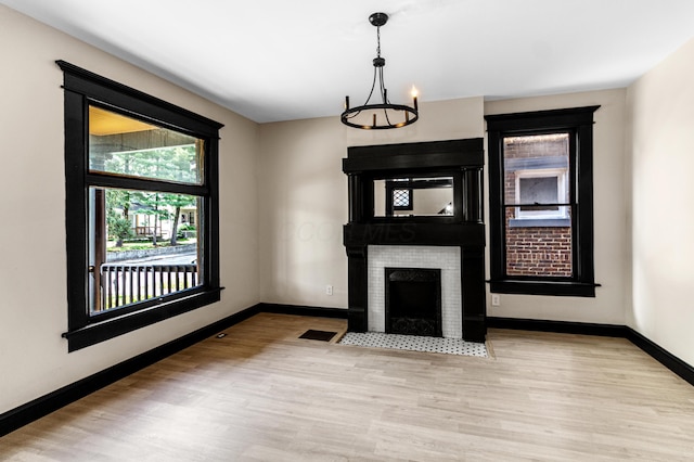 unfurnished living room featuring baseboards, visible vents, wood finished floors, and an inviting chandelier