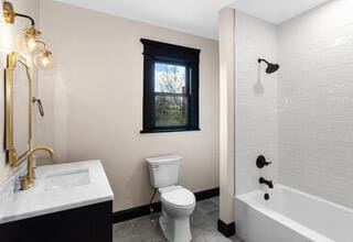bathroom with toilet, baseboards, shower / bathing tub combination, and vanity