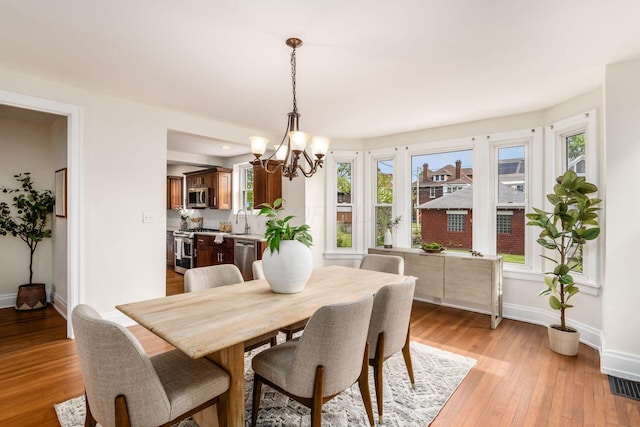 1800 Bryden Rd, Columbus, OH 43205 - dining area featuring a chandelier, baseboards, and light wood-type flooring