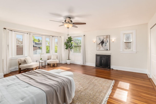 1800 Bryden Rd, Columbus, OH 43205 - bedroom featuring baseboards, wood finished floors, a fireplace with flush hearth, and a ceiling fan