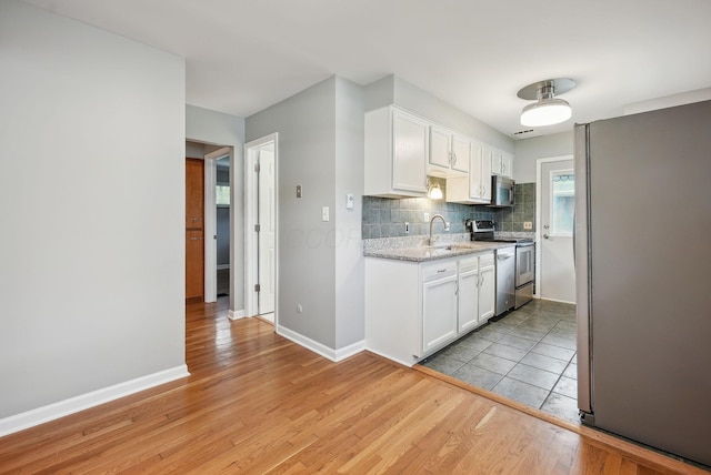 kitchen featuring backsplash, stainless steel appliances, white cabinetry, and a sink