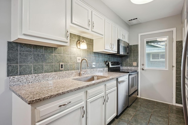 kitchen with white cabinets, backsplash, appliances with stainless steel finishes, and a sink